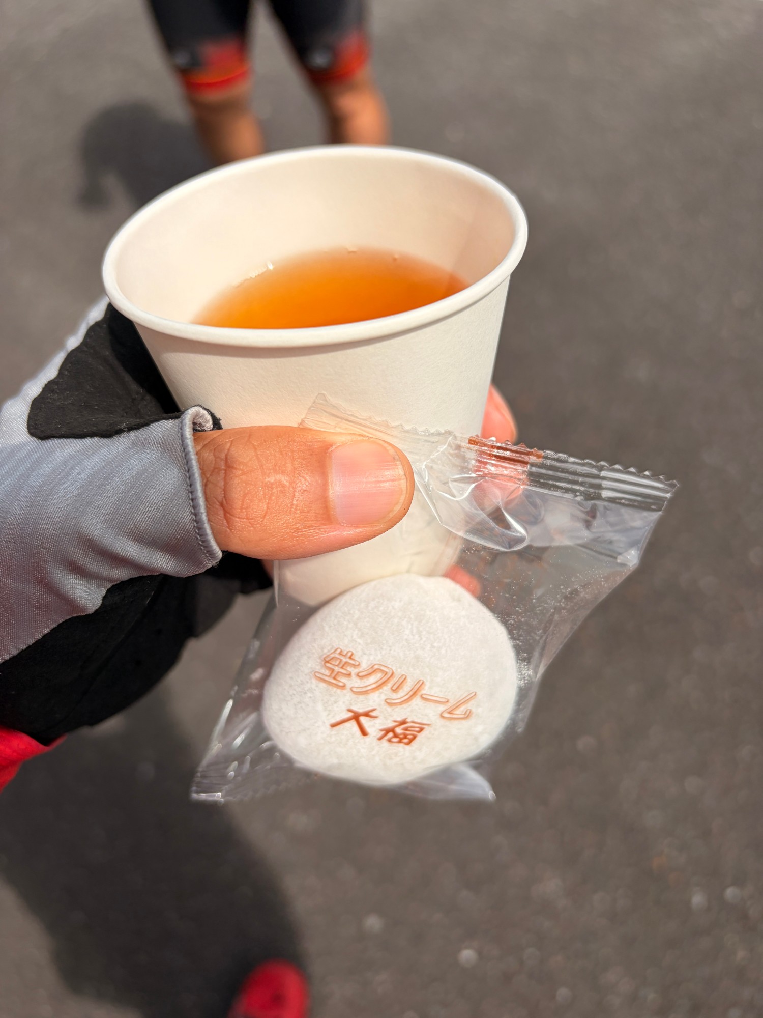 手に持った紙コップの飲み物と、個包装の生クリーム大福
