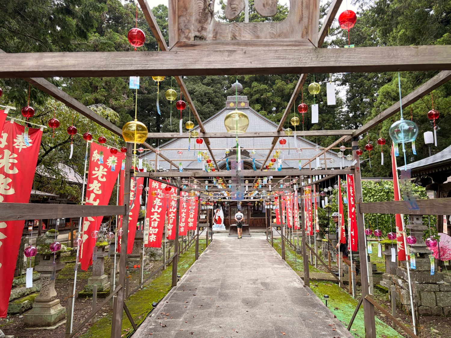 赤いのぼりが並ぶ参道の上に、色とりどりのガラスの風鈴が吊るされたお寺